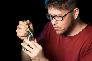 A man charging with liquid an electronic cigarette.Isolated on black background