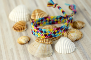 One simple handmade homemade natural woven bracelets of friendship on white wooden table and sea shells