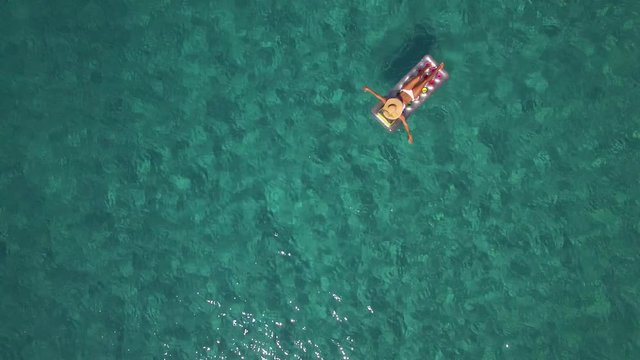 A young woman is sunbathing and swimming in the blue ocean, aerial - 1