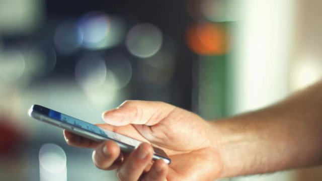 Using a Smartphone, sliding the screen and taping, close up shot with soft bokeh