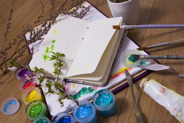 Creative artist workplace flat lay, mockup. top view on table with blank sketchbook, paintbrushes...