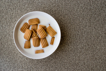 Baby biscuit with milk in white bowl.