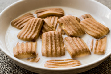 Baby biscuit with milk in white bowl.