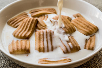 Pouring milk to baby biscuit.