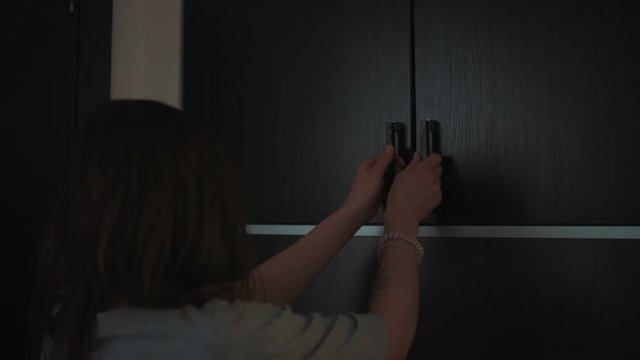 Unrecognizable young caucasian woman with tattoo on hand opens wall locker, lot of boxes falls out