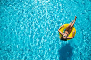 Obraz premium Beautiful woman enjoying the water in pool on inflatable