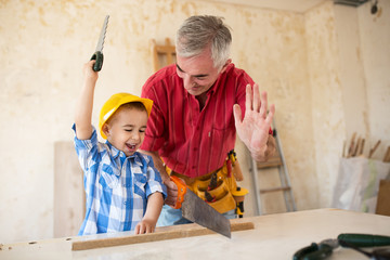 Smiling boy is helping to his granfather in workshop