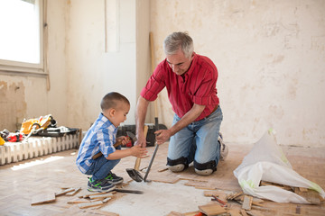 Grandson is helping to his grandfather in separating the old parqet