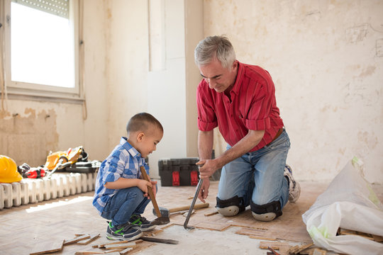 Grandsonis helping to his grandfather in separating the old parqet