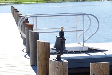 A pier bell resting on a pier on a pier on the dock of a small lake.