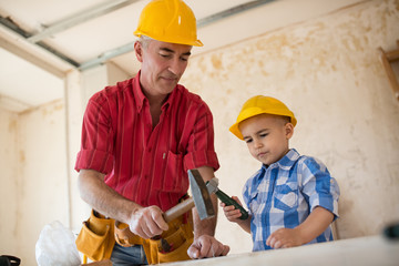 Grandson is helping grandfather in  a carpenter's workshop