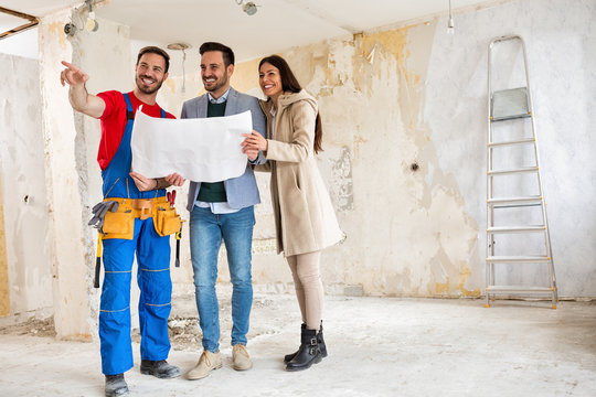 Builder handyman shows to young couple details blueprints of their home