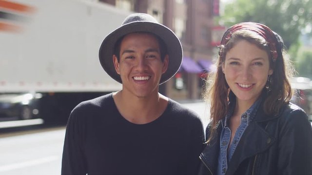 A young couple standing together on a city street and smiling, portrait