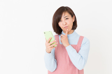エプロンをしたミドル女性　スマホ　考える