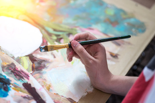 Asian man painting brush watercolors on paper.