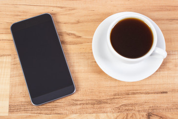 Fototapeta na wymiar Mobile phone with blank screen and cup of coffee
