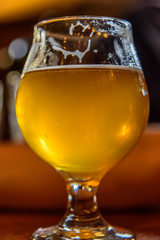 craft beer in tulip glass with suds and water droplets