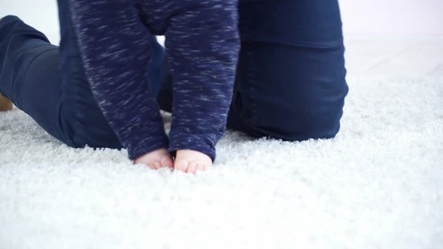 Young mother halping her 6 months to make the first steps closeup