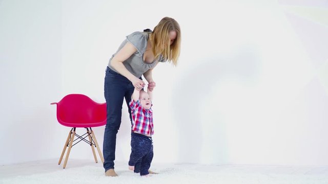 Young mother halping her 6 months to make the first steps