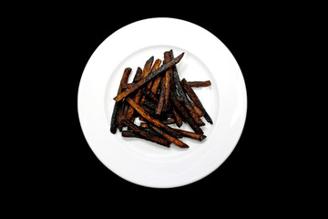 Blackened french potato fries on a white plate charred