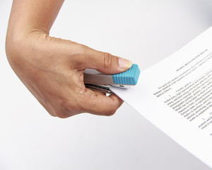 Close-up of woman's hand stapling paper on white background