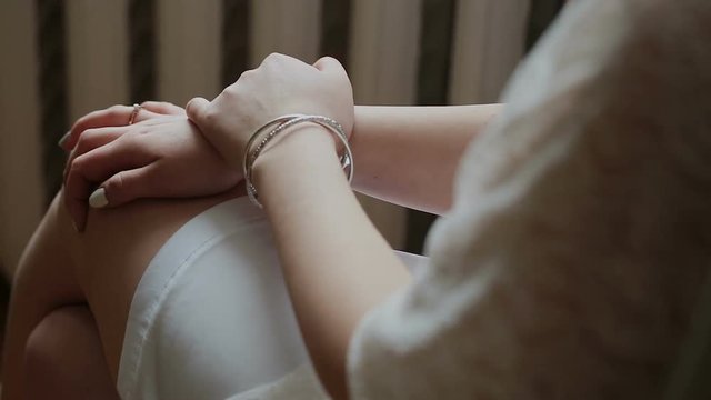 The hands of the girl on her knees in a nightgown