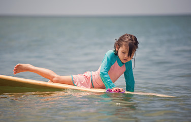 Little girl learn to surf at ocean