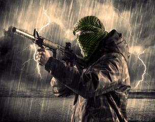 Dangerous armed terrorist with mask and gun in a thunderstorm with lightning