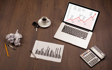 Computer desk with laptop and red arrow chart in screen
