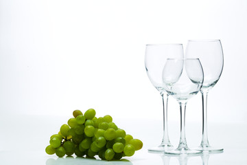 Wine glasses and a bunch of grapes on a white background