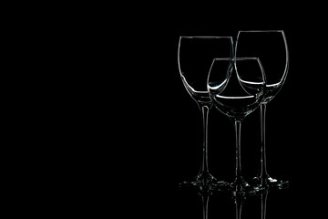 Glasses for wine and a bunch of grapes on a black background