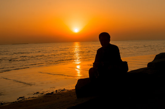 Silhouette of young man, standing alone, lonly by the sunset light of sea