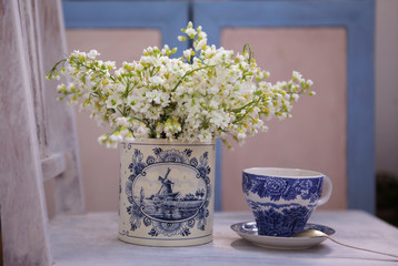 Still life with white flowers in the porcelain vase and the vintage cobalt china cup in the morning light  