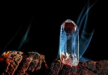 ein Bergkristall steht von Rauch umgeben in heißer Glut