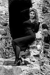 A young woman with blond hair and skin in a black elegant dress and high heeled shoes near the abandoned tunnel unravels her own secrets of her soul, the emphasis on psychology