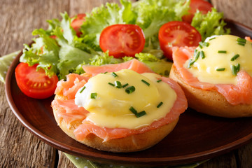 poached eggs with smoked salmon, hollandaise sauce and vegetables close-up. horizontal