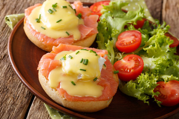 poached eggs with salmon, hollandaise sauce and vegetable salad close-up. horizontal