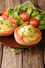 hearty breakfast: poached eggs with salmon and hollandaise sauce close-up. vertical