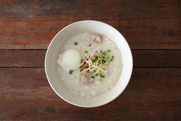 Pork rice porridge with egg on the wooden table. Top view, flat lay style.