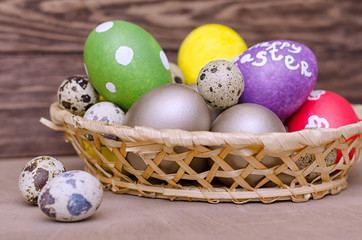 Multicolored easter eggs in the basket of wooden boards