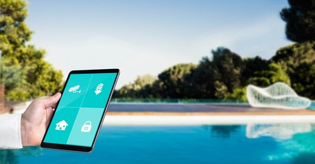 Hand using smart home application on tablet PC at poolside