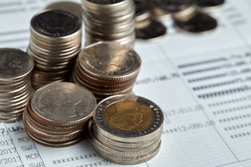 Coins stack with blue home toys on passbook. Saving, income and payment concept.