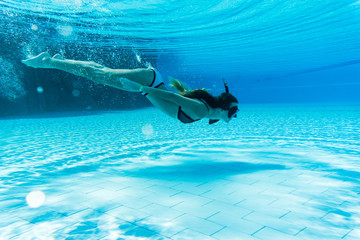 Woman wearing snorkeling mask swimming underwater in pool