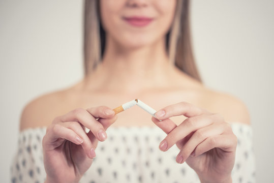 Happy Young Beautiful Woman Holding A Broken Cigarette,quit Smoking Concept.