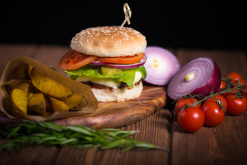 Large appetizing burger with beef, potatoes and cheese on a wooden surface. Close-up