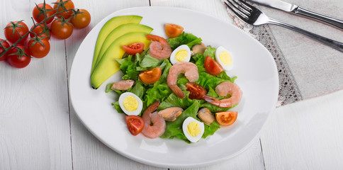 Delicious appetizing vegetable salad with seafood on a white plate. Close-up