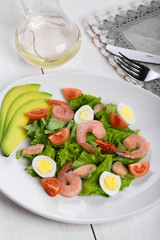 Delicious appetizing vegetable salad with seafood on a white plate. Close-up