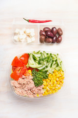 Healthy salad with tuna and vegetables  in plastic packaging for diet lunch on white wooden background, top view