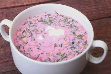 Popular spring cold soup okroshka with yoghurt. Okroshka in a bowl on wooden table. Selective focus