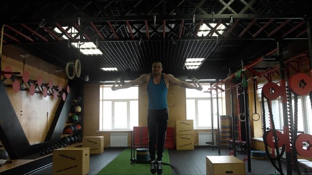 An athlete doing exercises on the rings in the hall of crossfit